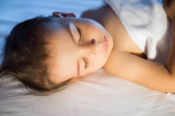 Retrato de cerca de la adorable niña durmiendo en la cama blanca en — Foto de Stock