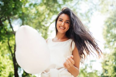 Güzel ve genç birbayan gülümseme pamuk şeker ile alt görünümü doğa arka plan üzerinde.