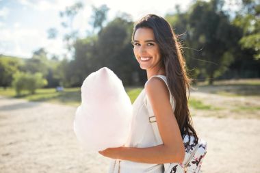 Pamuk helva ve rüzgarlı saçlı, parkta yürüyüş ve arkadan seyir sırt çantası ile güzel ve mutlu esmer kadın portresi. Gülümseme