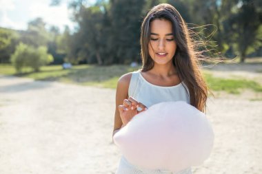 Parkta yürüyüş ve pamuk şeker yemek güzel esmer kadın. İlham