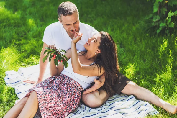 View of beautiful couple in love sitting on a picnic blanket out — Stock Photo, Image