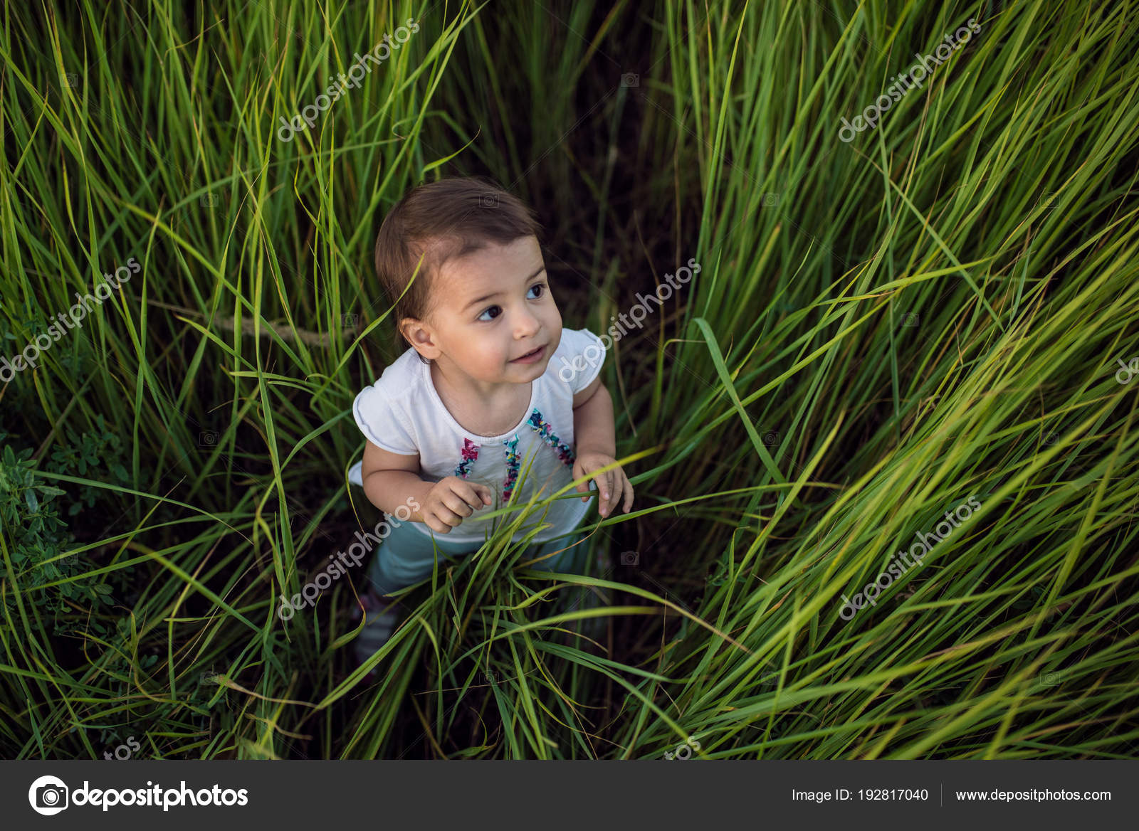 view from above of a cute toddler girl in a green grass background. Explore nature. Adventure time. Happy childhood. Outside walking in the park. Stock by ©iuricazac 192817040