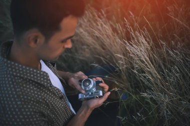 Yukarıdan alan, çim, doğa, arka plan üzerinde vintage fotoğraf makinesi ile genç bir adamın bir tatlı yakın çekim portre görüntüleyin. Seyahat. Resim arka plan için. Sonbahar. Yaz