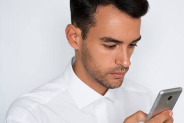 Genç adam cep telefonuyla gri arka plan üzerinde güzel yakın çekim portre. Akıllı telefonda konuşan işadamı. Kırpılan yüz.