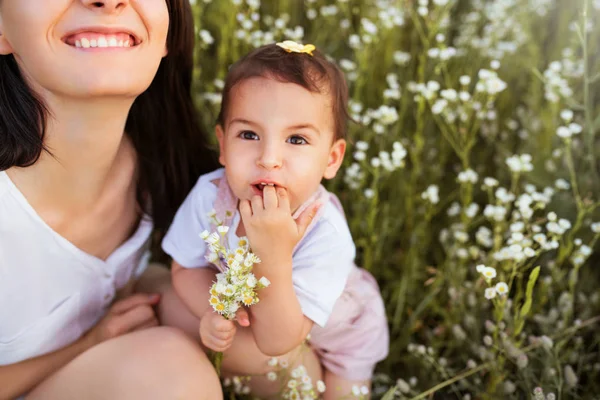 Счастливые милые мать и дочь, играющие на цветочном поле и смотрящие вверх, тошнотворный фон . — стоковое фото
