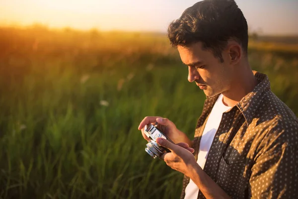 Yakışıklı genç yolcusu adam ile yeşil çayır üzerinde vintage fotoğraf makinesi. Seyahat kavramı — Stok fotoğraf