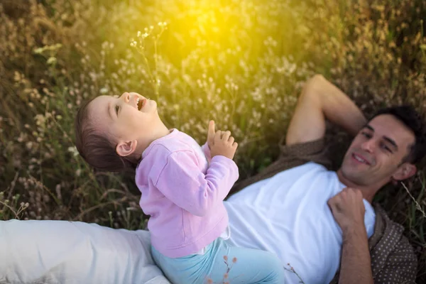 Yukarıdan bir oynama ve çim onun güzel mutlu yürümeye başlayan çocuk kızla gülerek mutlu genç Baba görüntüleyin. Onun bebek kız çayır on yürüyüş ile mutlu baba.