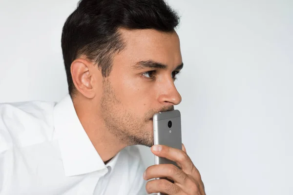 Портрет красивого мужчины отправляет текст на мобильный телефон изолированный на сером фоне. Технология и идея связи. Молодой кавказский бизнесмен позирует в студии со смартфоном . — стоковое фото
