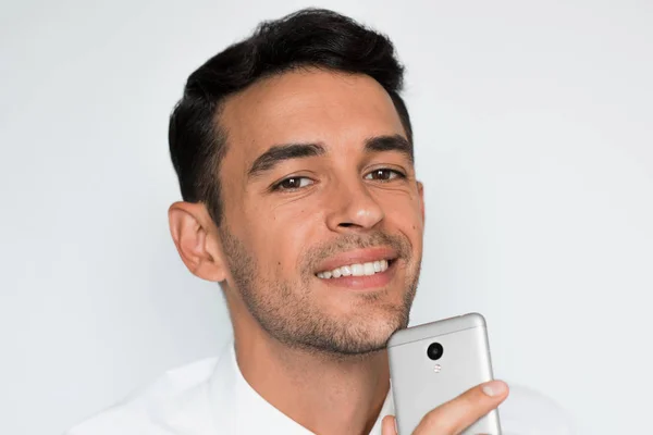 Retrato de hombre guapo enviar texto en el teléfono móvil aislado sobre fondo gris. Tecnología e idea de conexión. Joven hombre de negocios caucásico posando en estudio con teléfono inteligente . —  Fotos de Stock