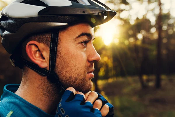 Portre profil yakışıklı ve ciddi bisikletçi yakın kadar onun koruyucu kask açık havada ve rota hakkında düşünme, seyir kapatın. Seyahat. Mavi t-shirt giyen spor lifestyleyoung binici.