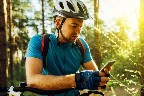 Utomhus skott av koncentrerad cyklist på cykel med navigator på smart telefon, utforska karta och söka GPS-koordinater medan Cykling i bergen. Resor, sport, aktiv livsstil och modern teknik. — Stockfoto