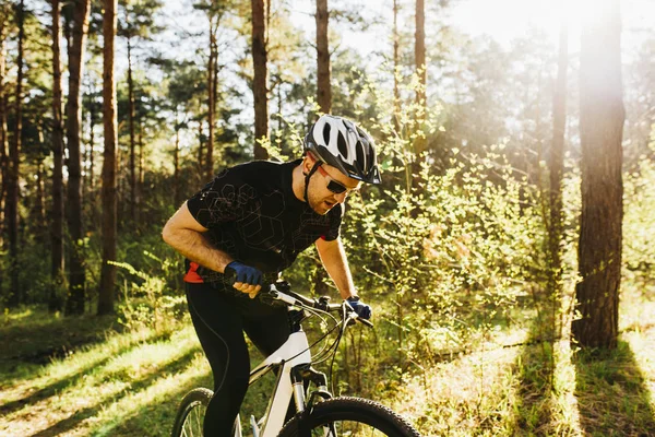 Stilig unga europeiska män bära skyddshjälm och svart sport kläder och glasögon ridning cykel utomhus i skog eller berg, njuta av morgonen rida, att ha lugn och självsäker uttryck. — Stockfoto