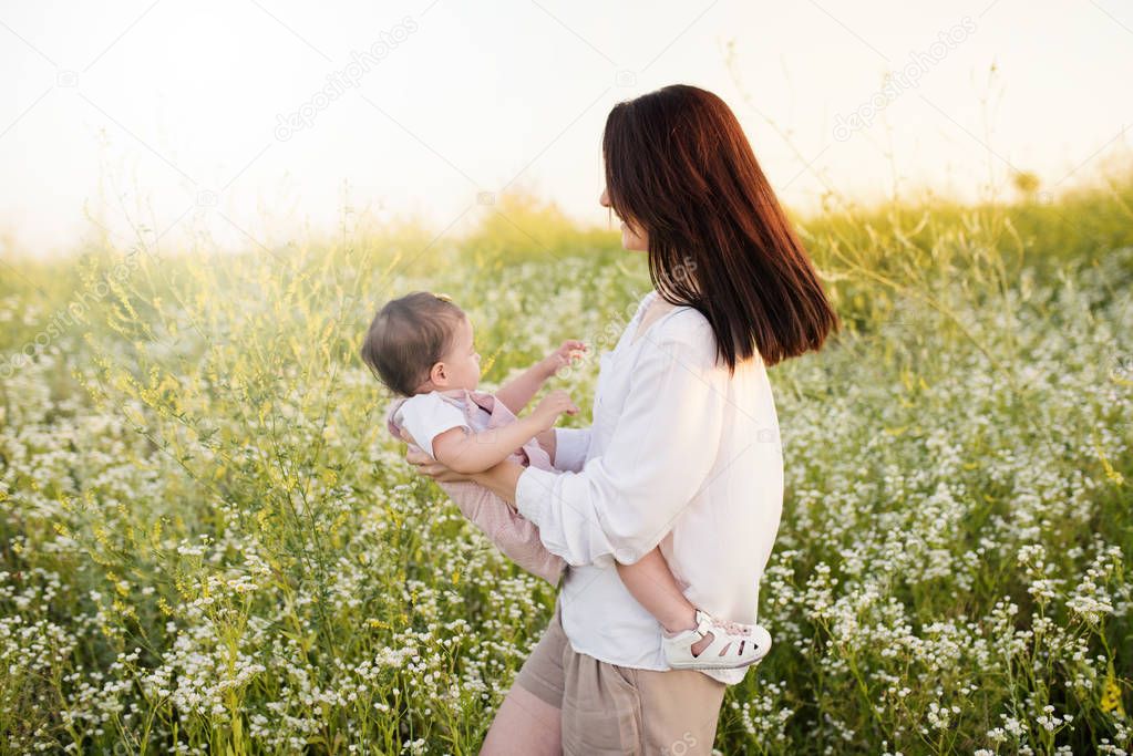 Happy pretty mother and daughter, toddler, baby, playing on a field, nature background. Motherhood and childhood