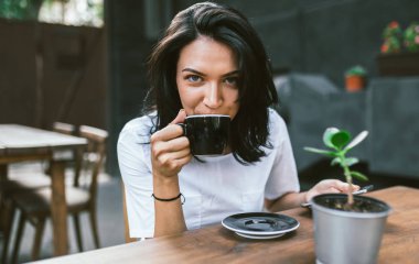 Avrupa kadın beyaz t-shirt içme kahve veya çay düşünceli büyük Kupası, giymiş mutlu ifade ile açık seyir yatay çekim zevk almak kırılmak. İnsanlar ve yaşam tarzı kavramı.
