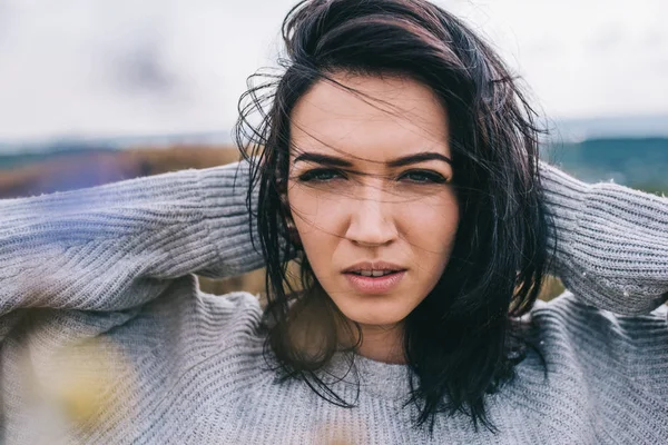 Retrato horizontal de jovem bela mulher morena posando contra a natureza, fundo do prado com cabelo ventoso. Pessoas e conceito de estilo de vida. Mulher sensual posando durante a viagem. Ideia de capa humor . — Fotografia de Stock