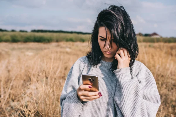 People, travel and lifestyle concept. Smart and pretty Caucasian woman texting on mobile phone, using wireless connection for social life, posing outside with windy hair and feeling free. Copy space.