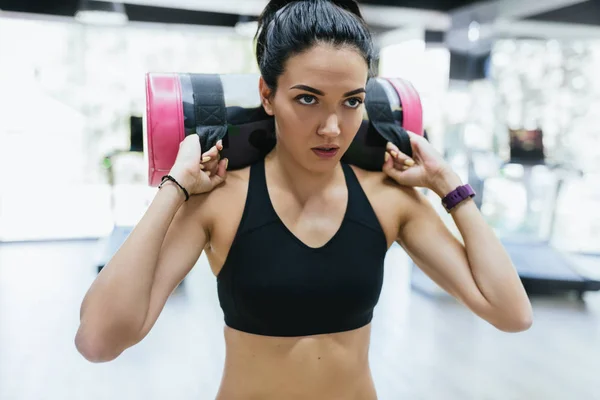 Portrait of brunette sporty woman working out with sandbag while exercise for butt legs in fitness club or gym. Attractive athletic female doing hard workout with weight training with copy space. — Stock Photo, Image