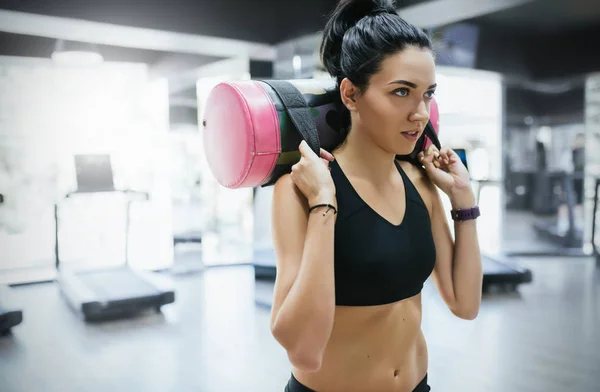 Close-up shot of brunette sporty woman working out with sandbag while exercise for butt legs in fitness club or gym. Attractive athletic female doing hard workout with weight training with copy space. — Stock Photo, Image