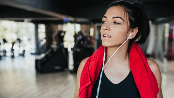 Horizontal portrait young Caucasian woman runner resting after workout session in the gym. Female jogger taking a break from running workout. People, sport and fitness concept. — Stock Photo, Image