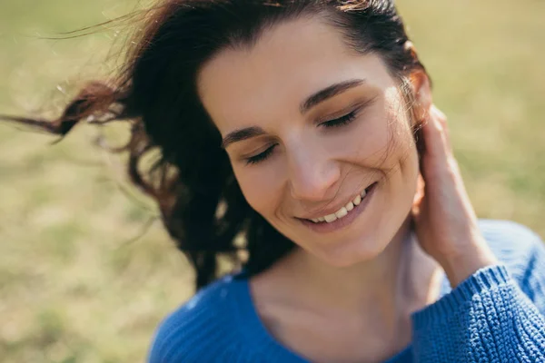 Close up retrato de atraente morena caucasiana jovem viajante com cabelo ventoso sorrindo e se divertindo no exterior da primavera ou no verão, conceito de viagem. Bonito sorriso feminino com olhos fechados . — Fotografia de Stock