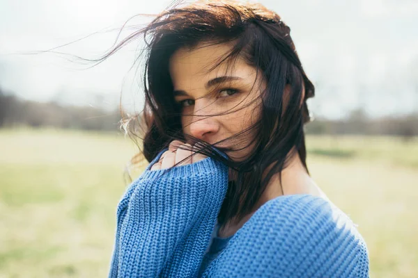 Retrato de atraente morena caucasiana jovem com cabelo ventoso, sonhando fora, na primavera ou no verão, sentado no parque. Sonhando fêmea com a mão na cara olhando para a câmera. Conceito de estilo de vida — Fotografia de Stock