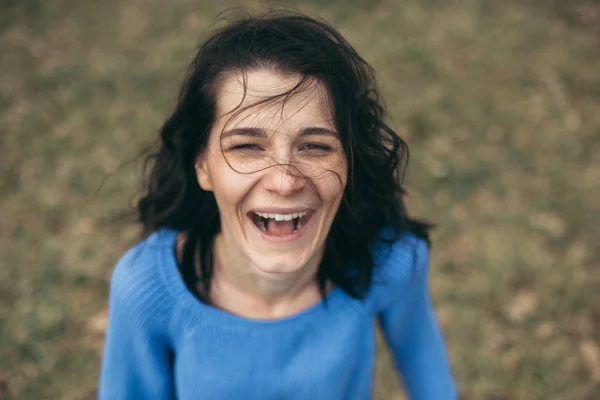 Young happy brunette woman smile with the wind blowing hair on nature background. Pretty female smiling, enjoy surprise. Top view of funny cheerful girl with healthy smile. Lifestyle concept. — Stock Photo, Image