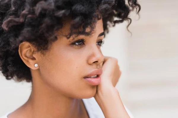 Cropped close-up shot of beautiful young dark skinned woman wearing casual with sad, pensive, reflective look, against white wall background with copy space for your text or advertising content. — Stock Photo, Image