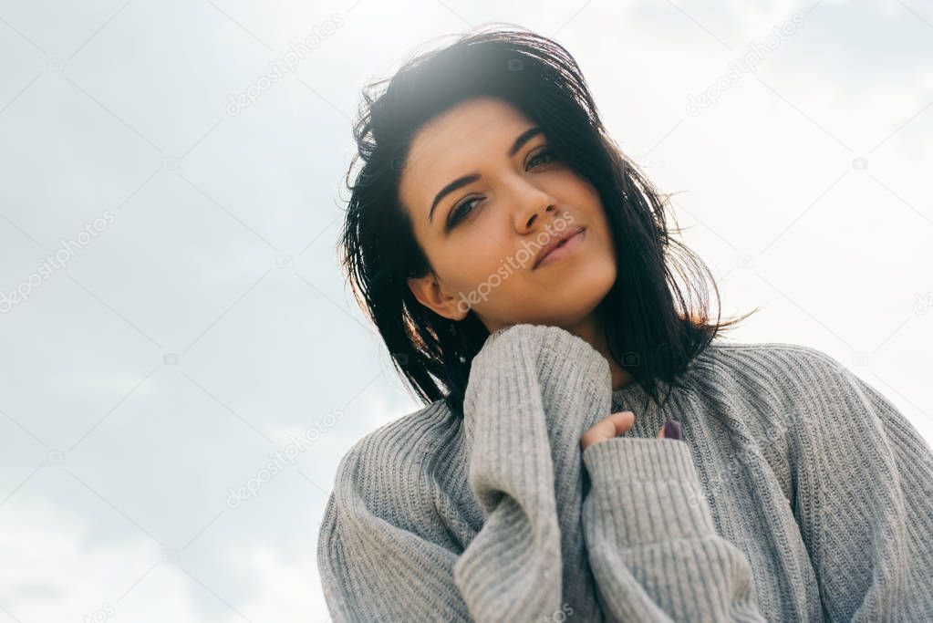 Bottom view portrait of dreamy attractive young woman being playful and carefree with beautiful smile posing on sunlight sky. Healthy outdoors lifestyle concept. Cover idea mood.