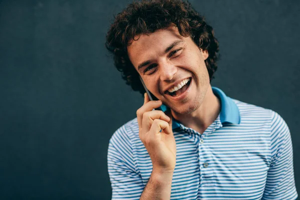 Close-up portrait of young man talking on mobile phone with his girlfriend. Happy male with curly hair resting outside making a call on his smart phone in the city street. Lifestyle, people — Stock Fotó