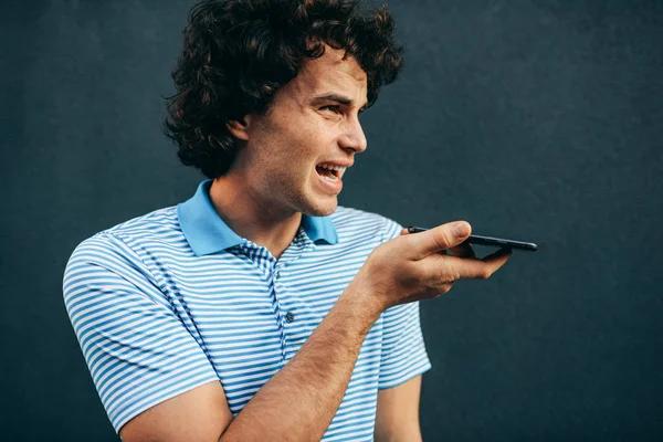 Young man talking on mobile phone with his girlfriend. Happy male with curly hair resting outside making a call on his smart phone in the city street. Lifestyle, people — Stok fotoğraf