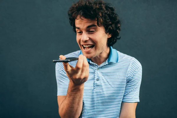 Retrato de un joven alegre hablando por teléfono móvil con su novia. Hombre feliz con el pelo rizado descansando afuera haciendo una llamada en su teléfono inteligente en la calle de la ciudad. Estilo de vida, gente —  Fotos de Stock