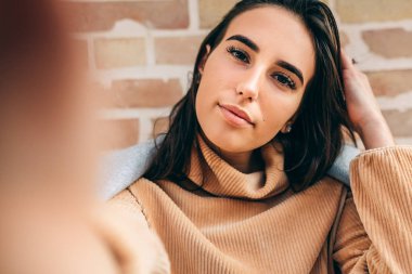 Sarışın, güzel bir kadının bej kazak giyip, Huş ağacının duvarına kendi portresini yaptığı yakın plan görüntüsü. Çekici esmer kadın selfie çekiyor. İnsanlar, seyahat, yaşam tarzı konsepti.