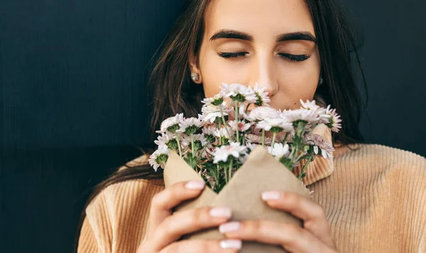 Retrato de close-up de bela jovem mulher cheirando as flores cor-de-rosa no dia ensolarado no parque. Mulher bonita recebeu um presente um buquê de flores de seu boyfreind na rua da cidade. Dia da mulher — Fotografia de Stock