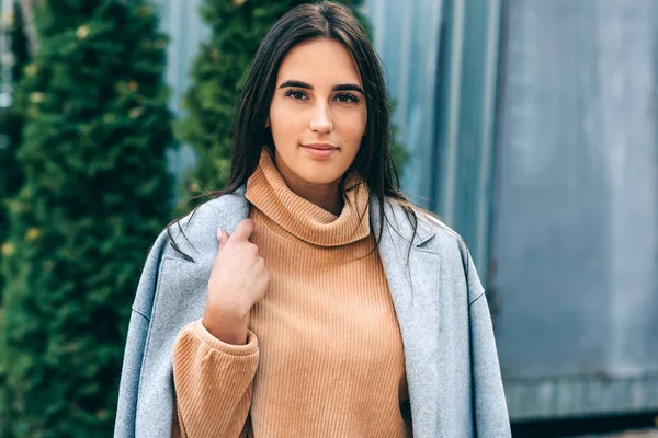 Young brunette woman wearing casual outfit, smiling and looking directly to the camera. Pretty female walking in the city street. — 스톡 사진