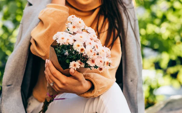 在阳光明媚的日子里,公园里,一位年轻女子戴着一束粉红色的花,被剪成了一副模样.漂亮的女性从她的男朋友那里得到了一份礼物。女人的日子 — 图库照片