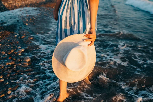 모자를 석양을 배경으로 해변을 여자의 모습이 스쳤다 여자들은 줄무늬 드레스를 — 스톡 사진