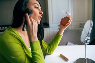 Güzel kadın blogcunun sosyal ağlarda blogu için yeni içerik yaratırken yan görüntüsü. Güzel bir kadın güzellik blogu için makyaj yapıyor. Kozmetik üzerine. Modern teknoloji, internet, blog yazma.