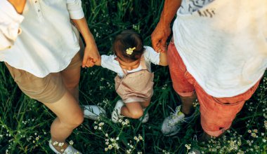 Saha doğasında kızıyla birlikte yürüyen güzel aile imajının üstünde. Dışarıdaki güzel küçük kızın el ele tutuşan kadın ve erkeğin en iyi görüntüsü. Tatil ve seyahat kavramı.