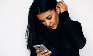 Esmer genç bir kadın cep telefonuna kısa mesajlar yazar, internetten alır, sarı kazak giyer, beyaz stüdyo duvarına izole edilmiş. Teknoloji ve insanlar kavramı