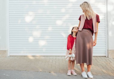 Güzel annenin tüm vücudu, okuldan eve dönen küçük kızına bakıyor. Güzel kız annesini kucaklıyor ve birlikte mutlu oluyor. Kadın çocuğunu dışarıda fotokopi çekerek kucaklıyor..