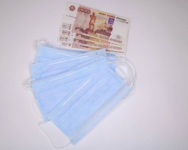 Bir takım tıbbi koruyucu maskeler ve para.