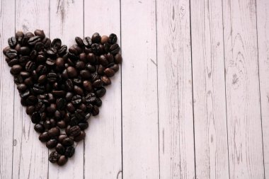 Kalp şeklinde kahve çekirdekleri ahşap bir masada yatıyor.