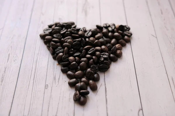 Coffee beans in the form of a heart lie on a wooden table