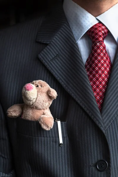 Primer plano con elegante hombre de negocios elegante mantener osito de peluche pequeño en su bolsillo chaqueta traje de pecho. Concepto de negociaciones formales . — Foto de Stock