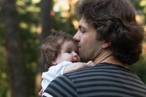 Parkta bir yürüyüş için onun kollarında küçük mavi gözlü kızı tutan baba. Yaz günü, Aile doğa yürüyüşü, güneşli