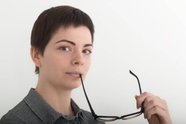 Siyah ve beyaz ekose gömlekli cidden ağzına yakın gözlük tutan genç çekici kız. Beyaz arka plan, maske dahil izole