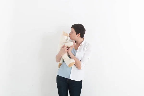 Женщина стоит и целует свою белую и прекрасную плюшевую кошку . — стоковое фото