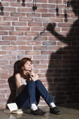 Bir korku veya korku gerilim kitap okuma katta oturan beyaz kız. Dramatik aydınlatma kızlar gözleri geniş açık ve uzun gölgeler kadının onu yakınındaki duvara bıçakla. Dehşet ifade