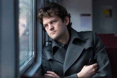 Tren ile seyahat. Üzgün bir adam tren ile seyahat, pencereden bakıyor ve elinde telefon sıkma karşılıksız aşk hakkında düşünme. Yalnız bir boş tren Vagon araçla. Gerçek insanlar serisi.