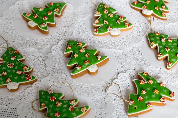 Pan de jengibre pintado en forma de árbol de Navidad sobre un fondo de servilleta blanca. Galletas de árboles de Navidad - decoración de hielo colorido . —  Fotos de Stock